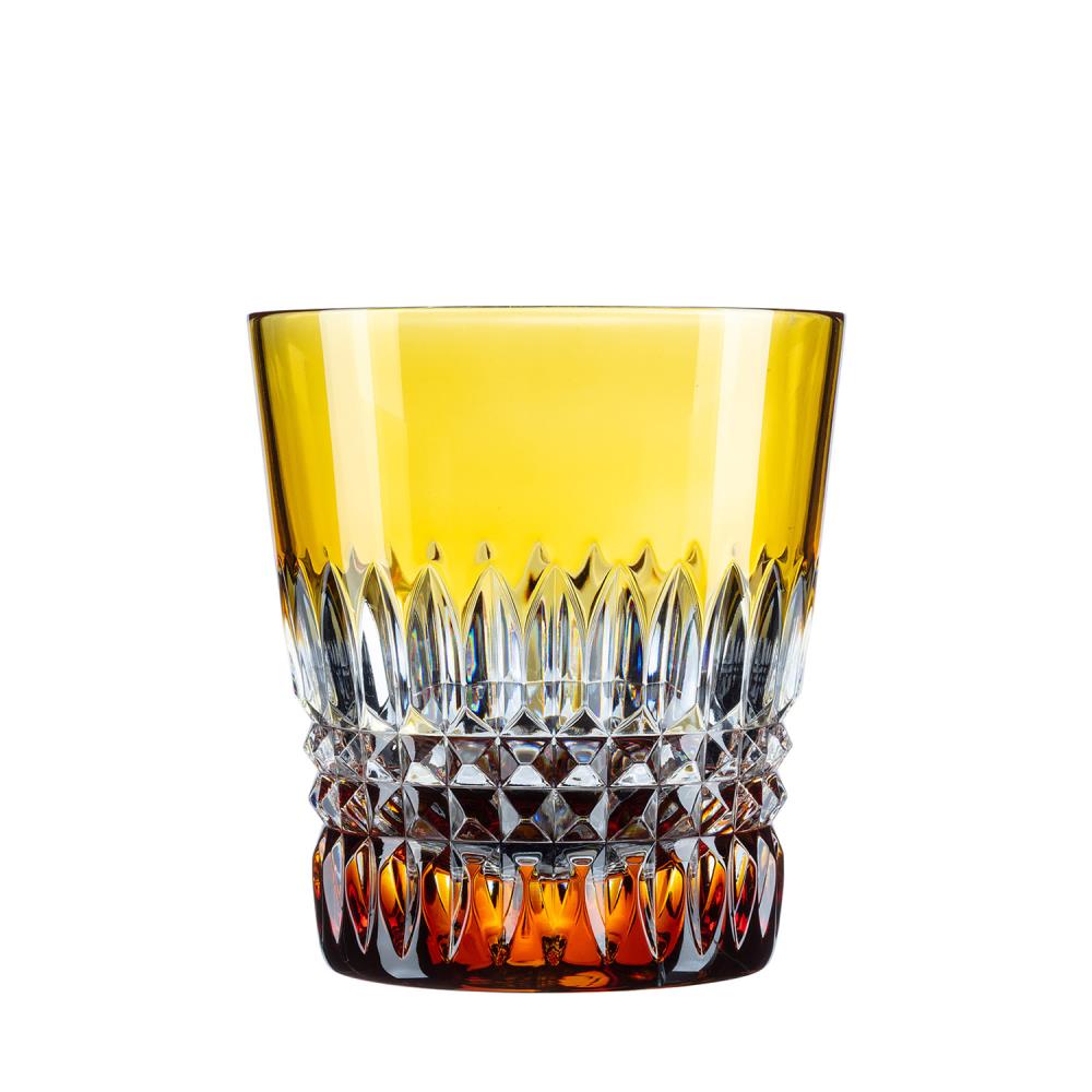 Amber-coloured crystal drinking glass with intricate cut patterns. Smooth at the top, with vertical pointed facets in the middle. A sparkling diamond pattern at the bottom and on the base, lending the glass rich texture and brilliance.
