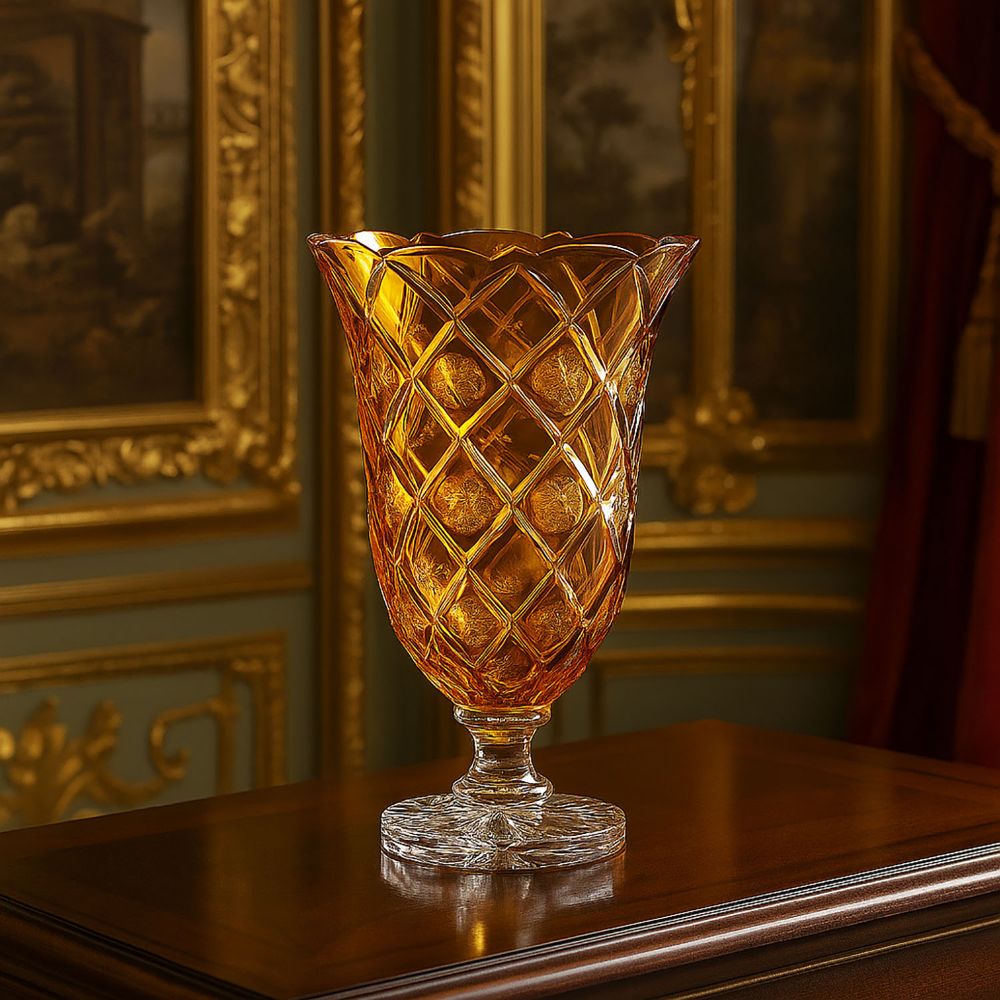 Tall, amber-coloured crystal vase with an elegant diamond pattern, partly featuring round medallions. Wavy rim, cut base on a dark wooden table. Gold-framed artworks in the luxurious background.